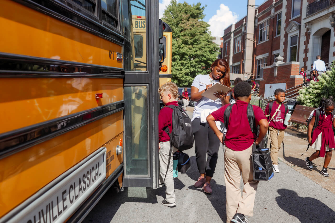 Students get on a Nashville Classical schoolbus while a teacher supervises