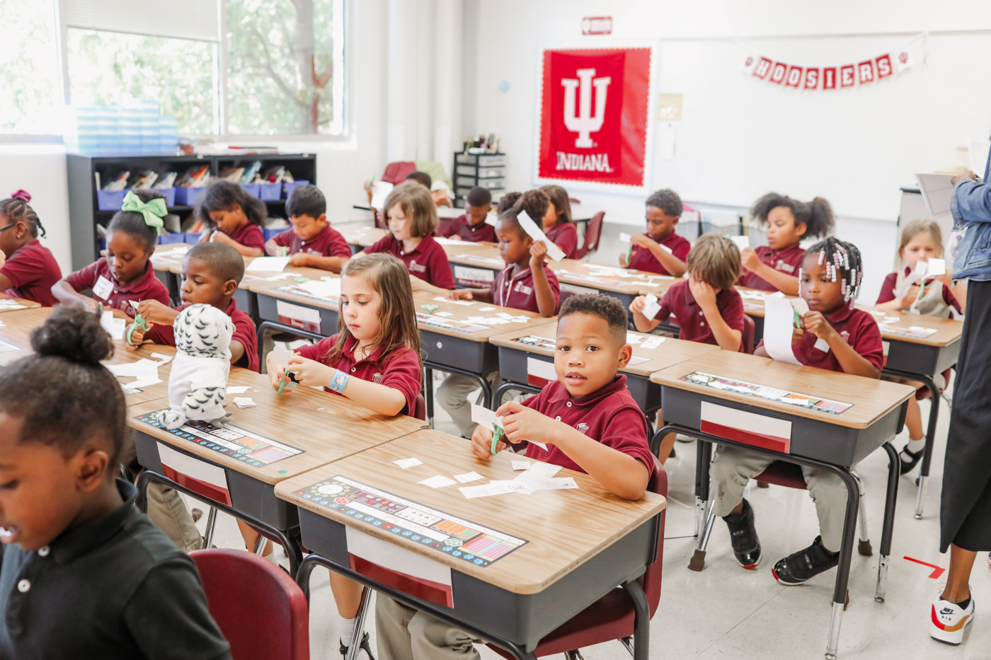 A group of students sit at their desks using scissors